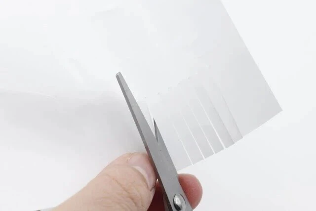 ダイソーの折りたたみハサミ（スマートタイプ、グリーン、ブルー）で紙を切る様子