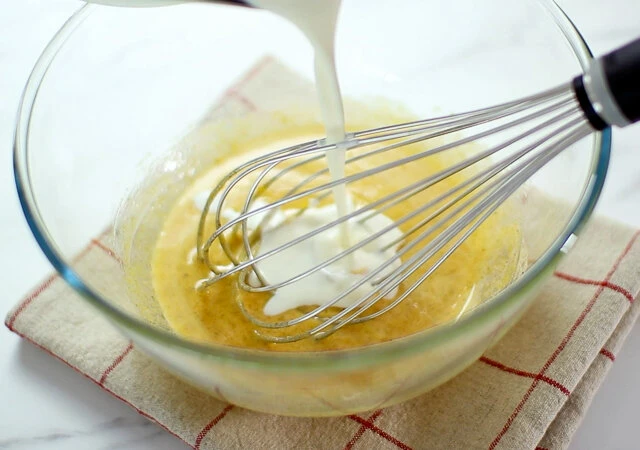 焼かないプリンタルト　レシピ　卵黄のボウルに温めた牛乳クリームを注ぎながら混ぜる