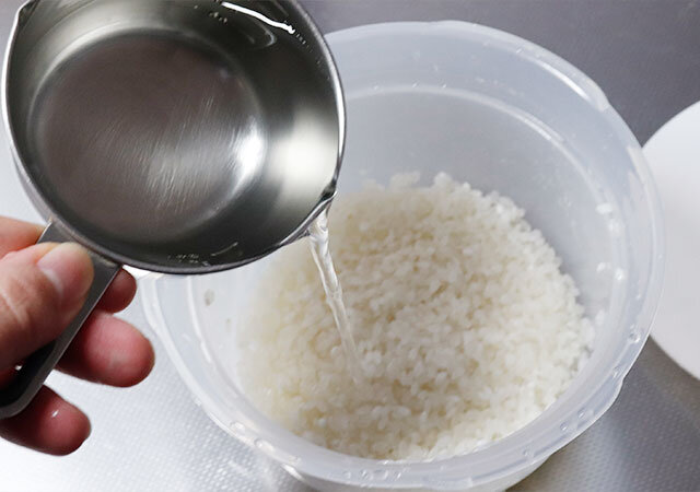 ダイソーの電子レンジ調理器（ご飯一合炊き用）Wにお米と水を入れる様子