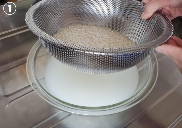 ボウルの中にざるを重ね米を入れ、水をたっぷり注ぎ、ざるを持ち上げ水を捨てる。