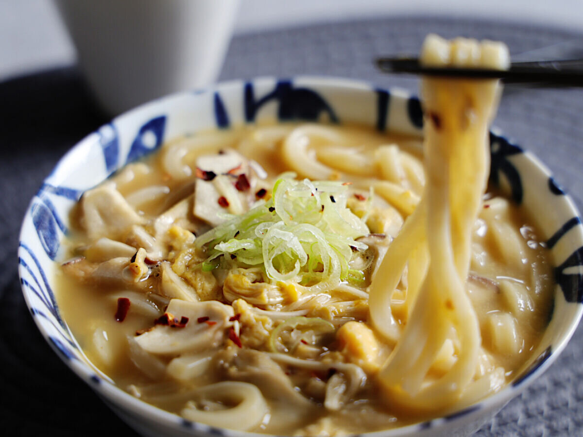 完成したきのこのかき玉うどんを箸で持ち上げている様子。刻みネギと唐辛子がトッピングされている 完成したきのこのかき玉うどんを箸で持ち上げている様子。刻みネギと唐辛子がトッピングされている