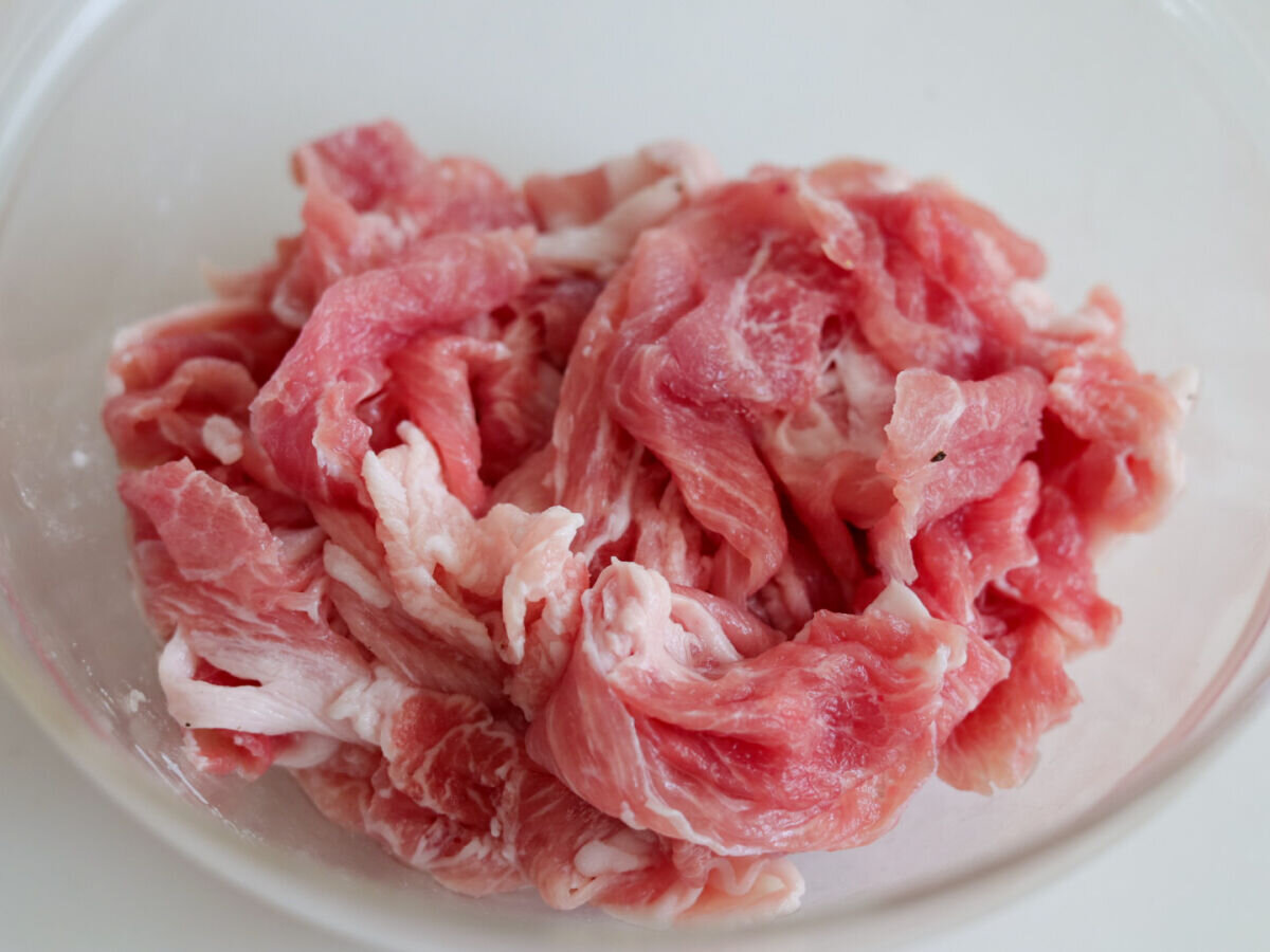 透明なボウルに入った生の豚こま切れ肉のアップ 透明なボウルに入った生の豚こま切れ肉のアップ