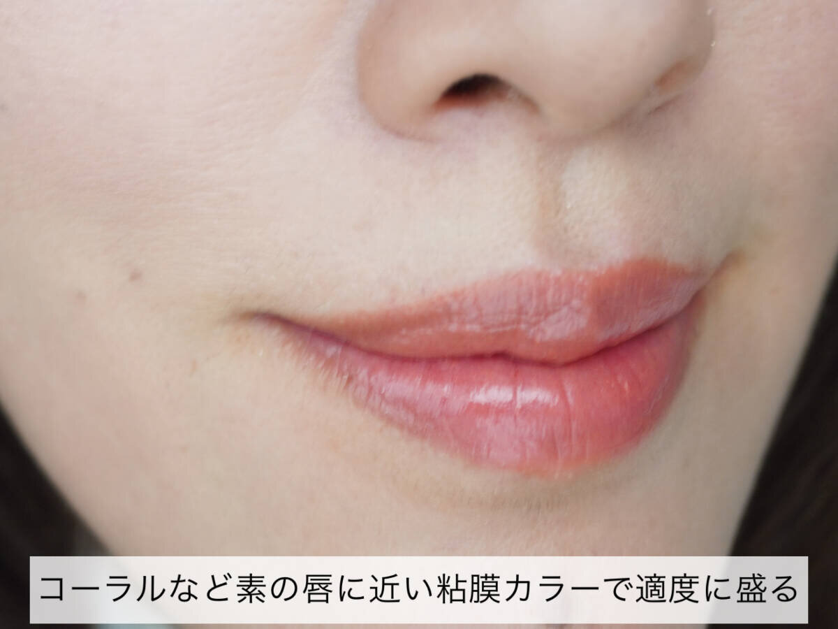 女性の口元のアップ。唇に粘膜カラーのリップが塗られ、自然なツヤがある。 女性の口元のアップ。唇に粘膜カラーのリップが塗られ、自然なツヤがある。
