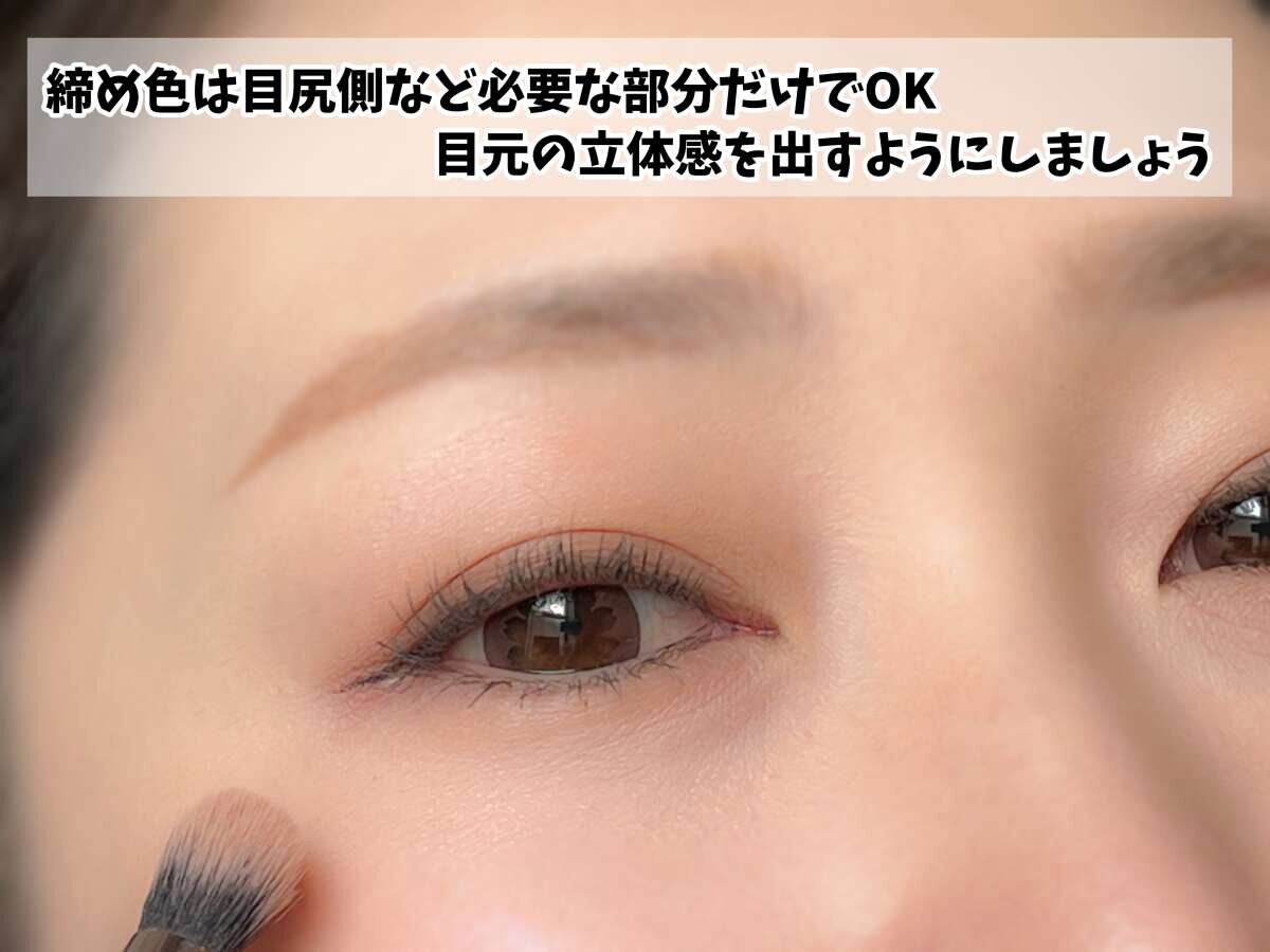 女性がアイシャドウブラシで目尻に締め色をのせ立体感を出している様子