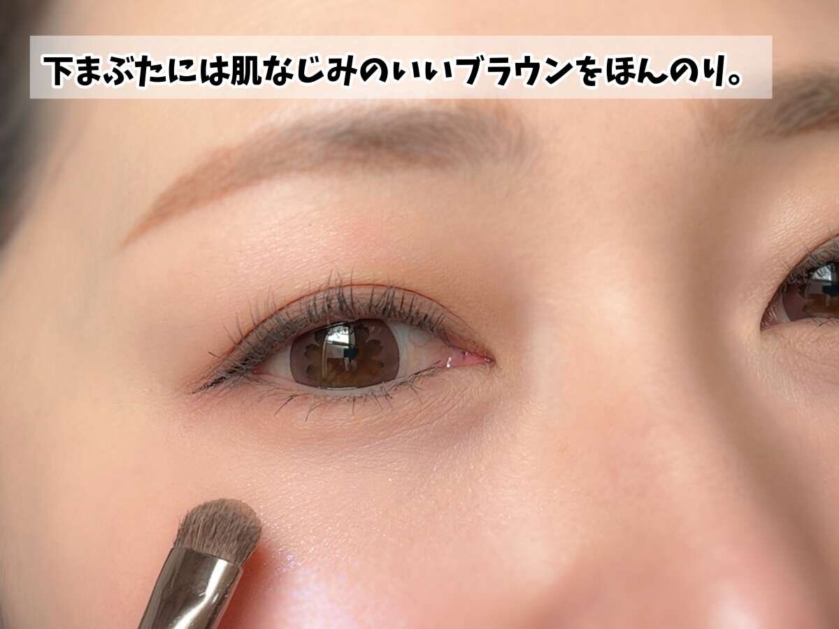 女性がアイシャドウブラシで下まぶたに淡いブラウンをほんのり入れている