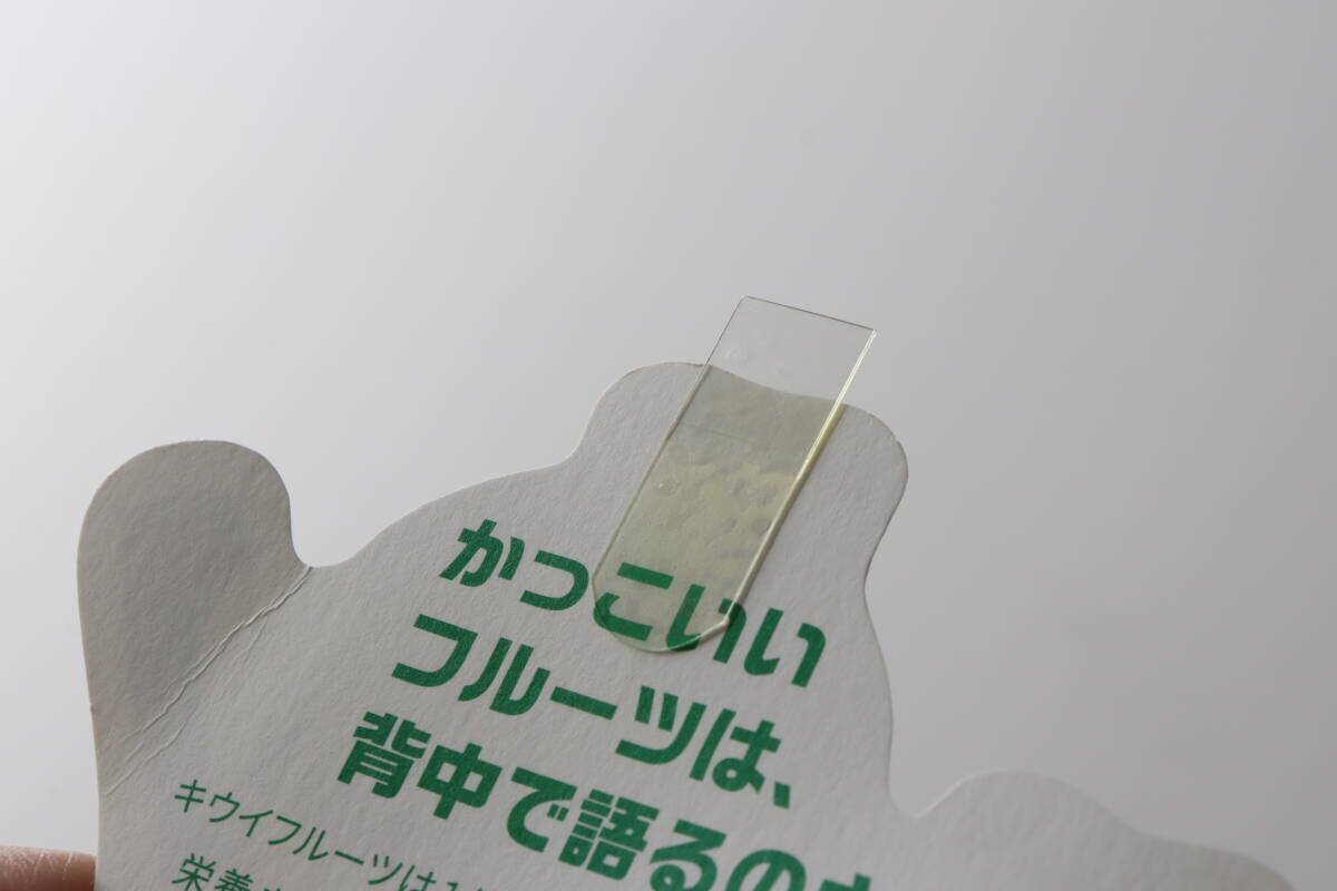 一張卡片的背面貼著一條透明的彈性膠帶,上面寫著:“酷炫的水果用它的背面說話。” 「かっこいいフルーツは、背中で語るのさ」と書かれたカードの裏面に透明な伸びるテープを貼っている