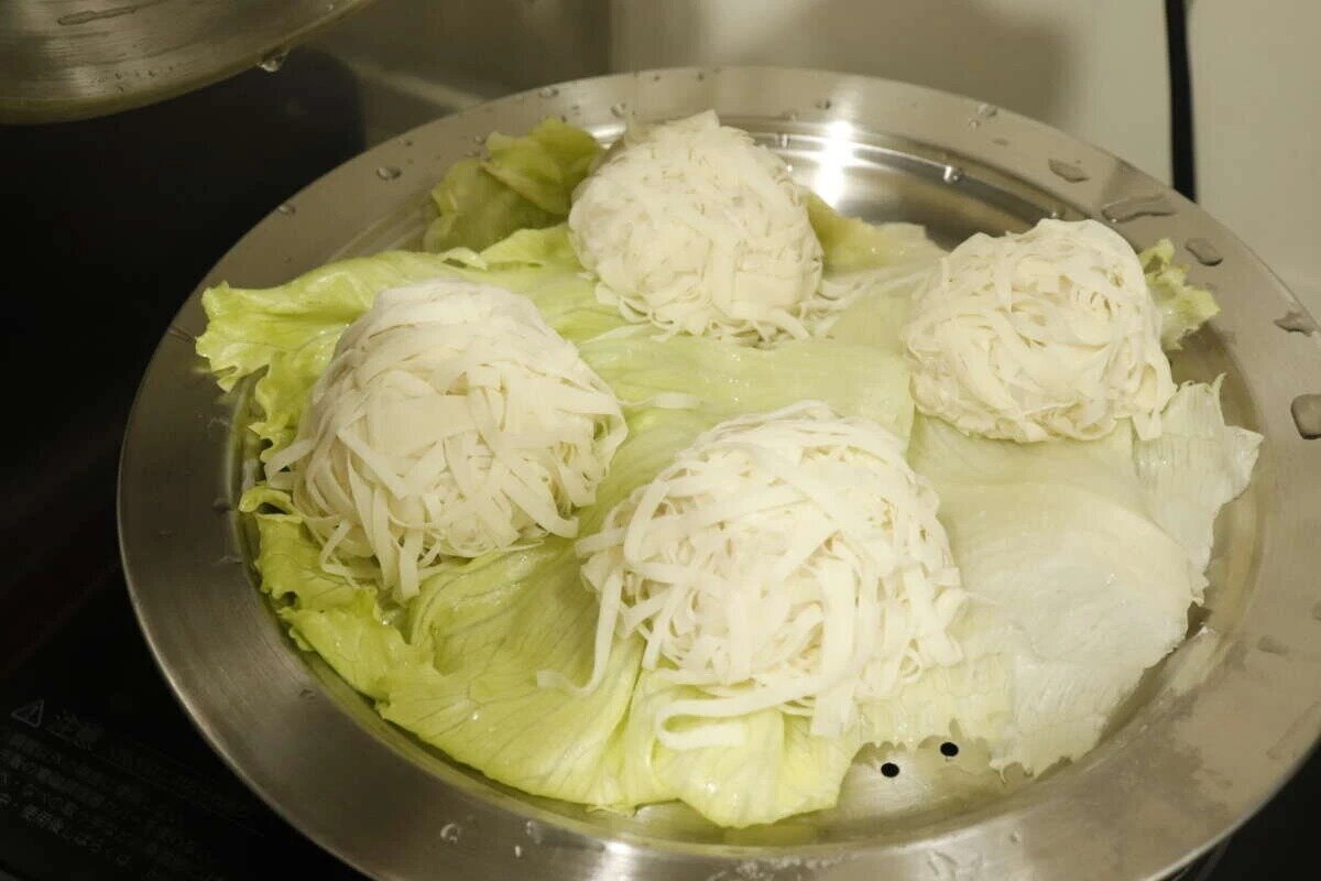 不鏽鋼蒸盤上放著生菜,生菜上面放著四塊圓形的白色食物。 ステンレス蒸しプレートの上にレタスと、その上に丸く成形された白い食材が4つ乗っている