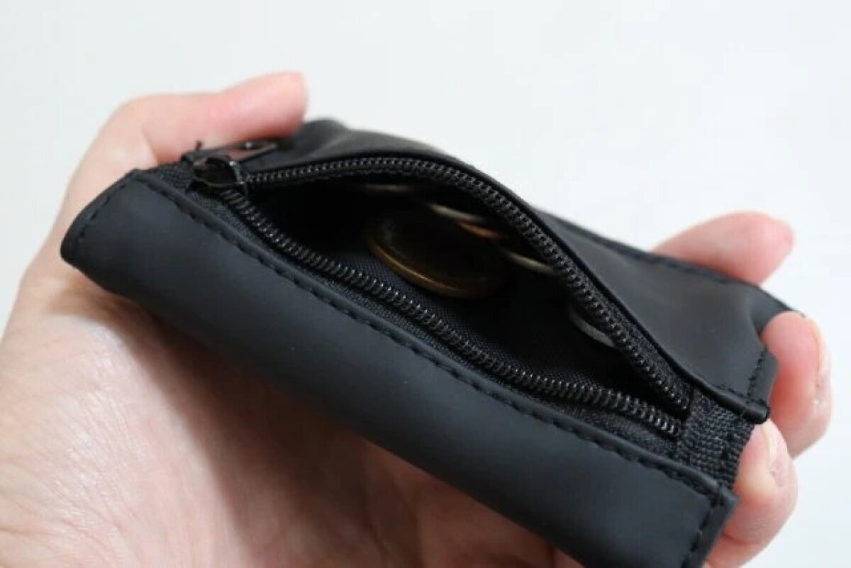 黒い三つ折り財布のファスナー付き小銭入れに小銭が入っている