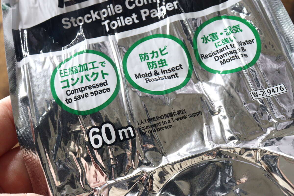 特寫鏡頭展示了手指捏著的鋁製包裝上的說明文字,例如“防黴防蟲”和“防洪防潮”。 指で持たれたアルミ包装に書かれた「防カビ防虫」「水害・湿気に強い」などの説明文のクローズアップ。
