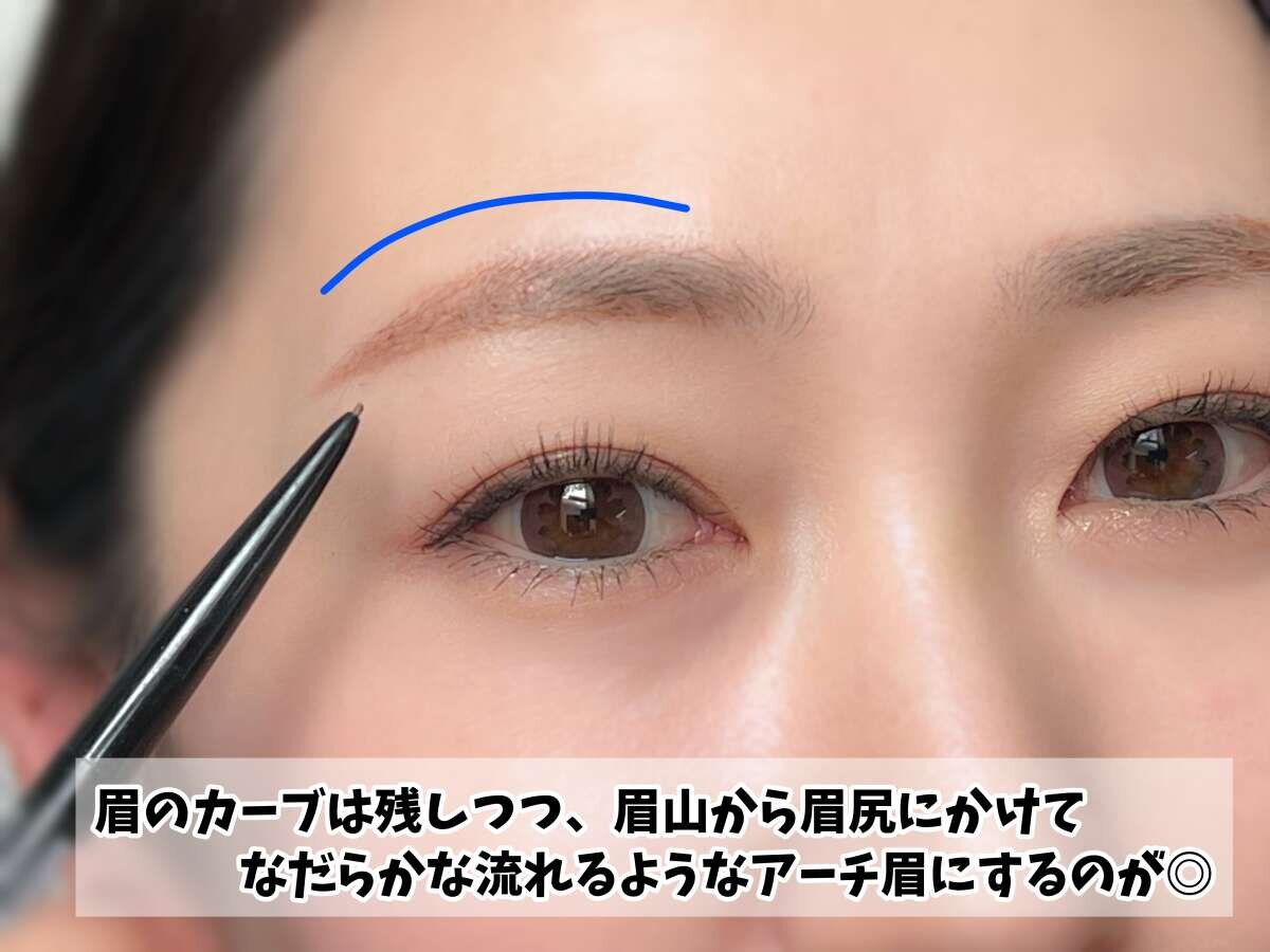 眉ペンシルで眉を描き、なだらかなアーチ眉のラインを青い線で示している女性の顔のアップ 眉ペンシルで眉を描き、なだらかなアーチ眉のラインを青い線で示している女性の顔のアップ