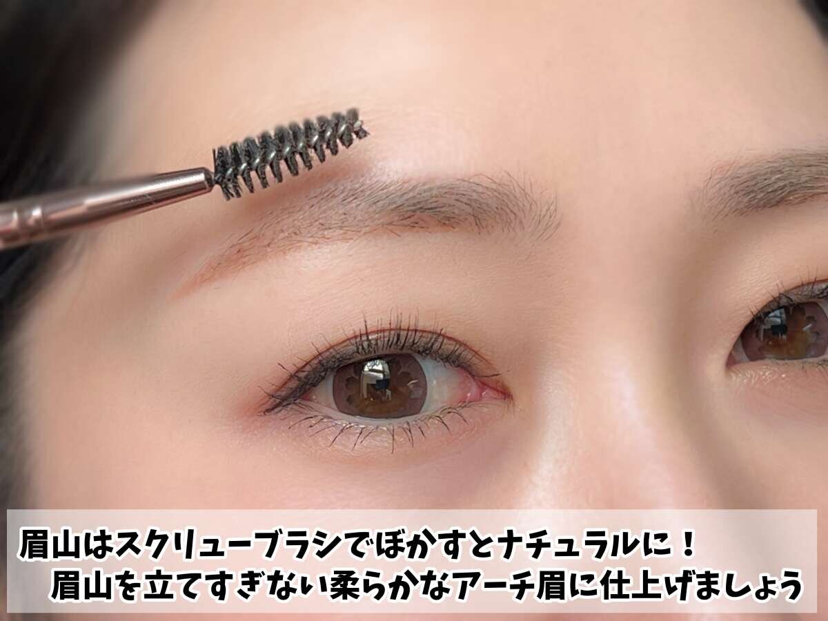 スクリューブラシで眉山をぼかし、眉を整えている女性の顔のアップ スクリューブラシで眉山をぼかし、眉を整えている女性の顔のアップ