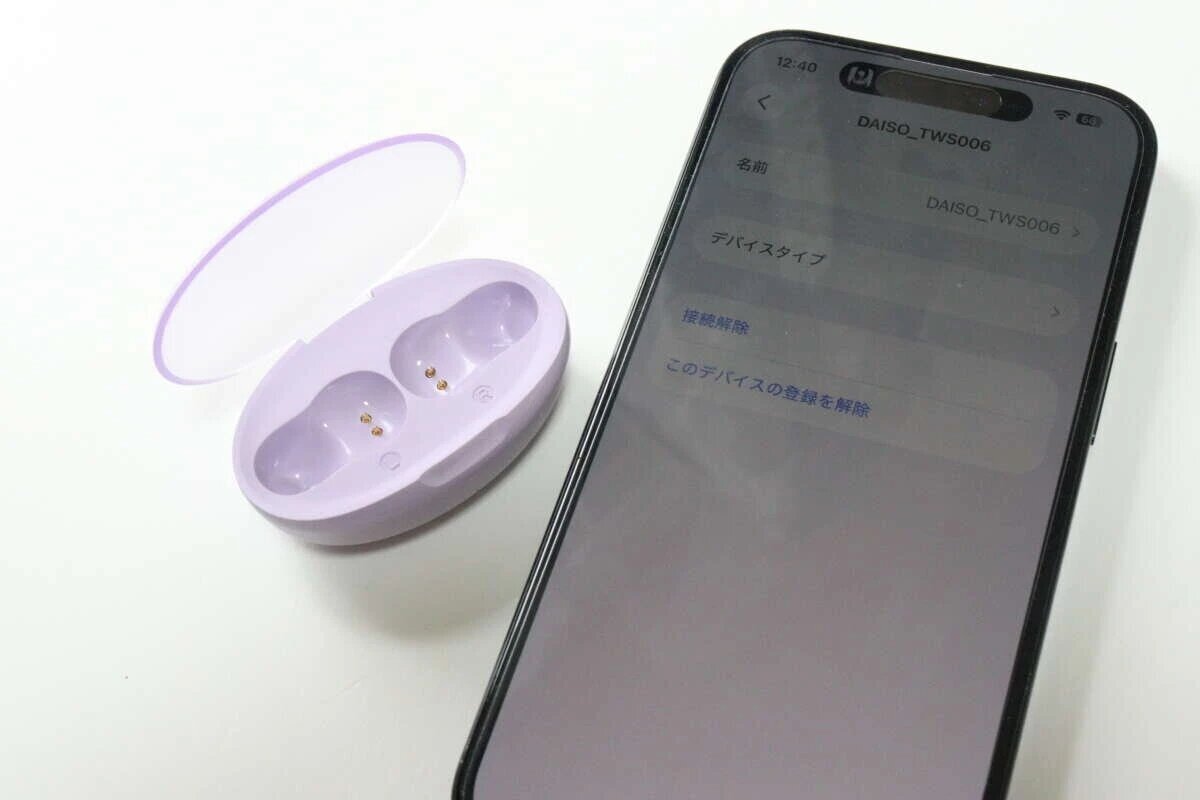 一個紫色的無線耳機充電盒和一部顯示藍牙設定介面的智慧型手機。 紫色のワイヤレスイヤホン充電ケースと、Bluetooth設定画面が表示されたスマートフォン