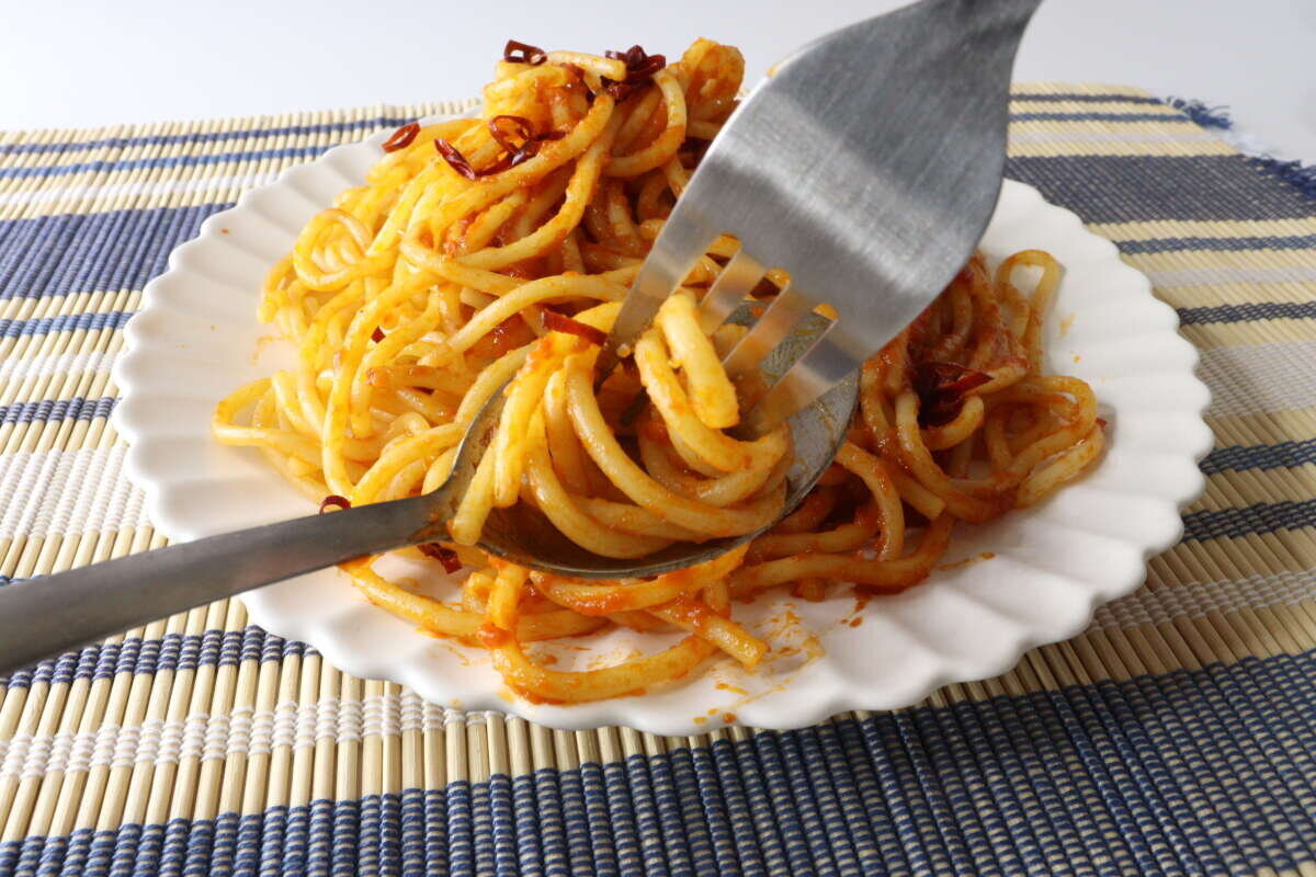 畫面中有人用不銹鋼湯匙和叉子舀起番茄醬義大利麵。 トマトソースのパスタをステンレス製スプーンとフォークで絡め取っている様子