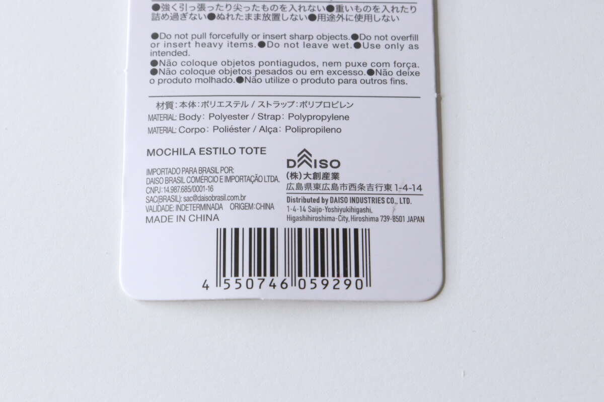 這是手提式背包的產品標籤背面。標籤上包含條碼、產品資訊和詳細警告。 トート型バックパックの商品タグの裏面。バーコード、商品情報、注意書きが詳細に記載されている。