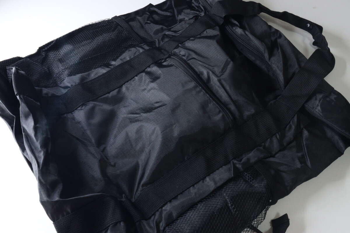 圖中展示的是一款展開的黑色手提式背包,可以看到網狀口袋和拉鍊口袋。 黒いトート型バックパックが広げられた状態。メッシュポケットやファスナー付きポケットが見える。