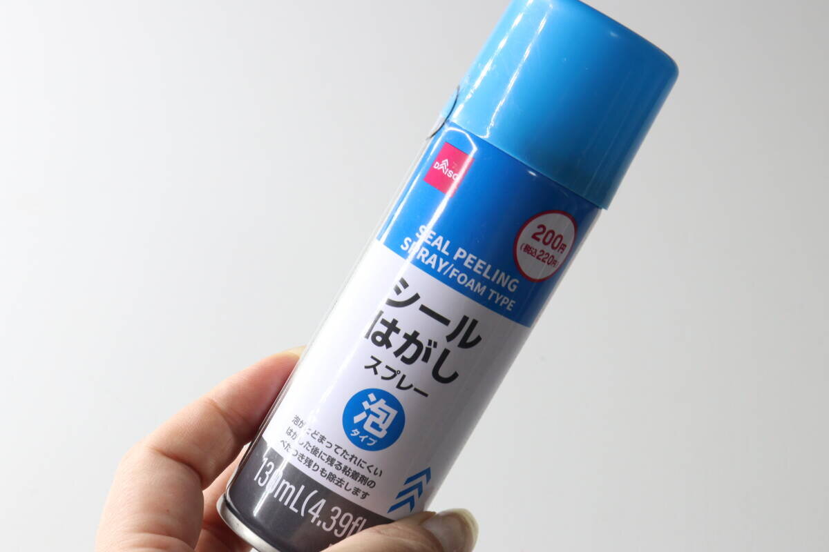 一位女士的手拿著一罐從大創(Daiso)買來的貼紙去除噴霧。 女性の手がダイソーのシールはがしスプレー缶を持っている様子