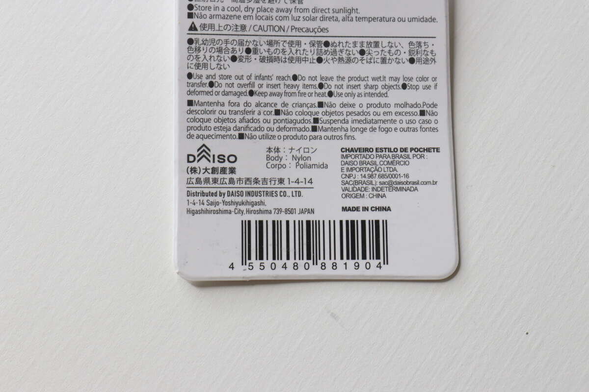 腰包式鑰匙圈背面產品資訊標籤的特寫。 ウエストポーチ風キーホルダーの裏面にある商品情報タグのアップ