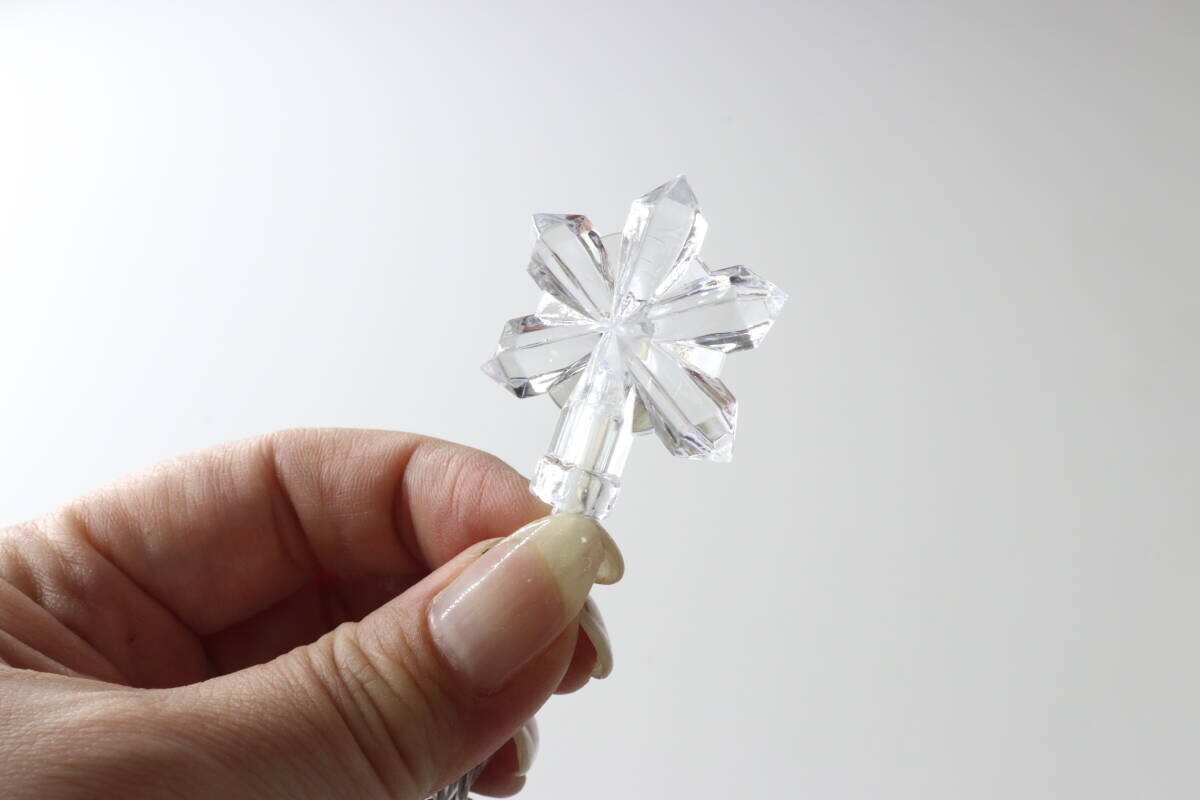 一盞雪花圖案的燈,夾在手指間。 指でつまんで見せている雪の結晶モチーフのライト