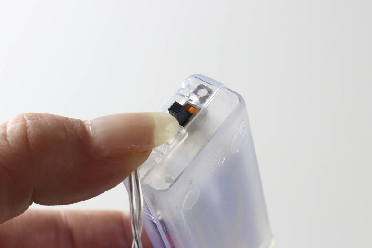 圖片顯示有人正在用手指操作電池盒上的開/關開關。 指で電池ボックスのON/OFFスイッチを操作している様子
