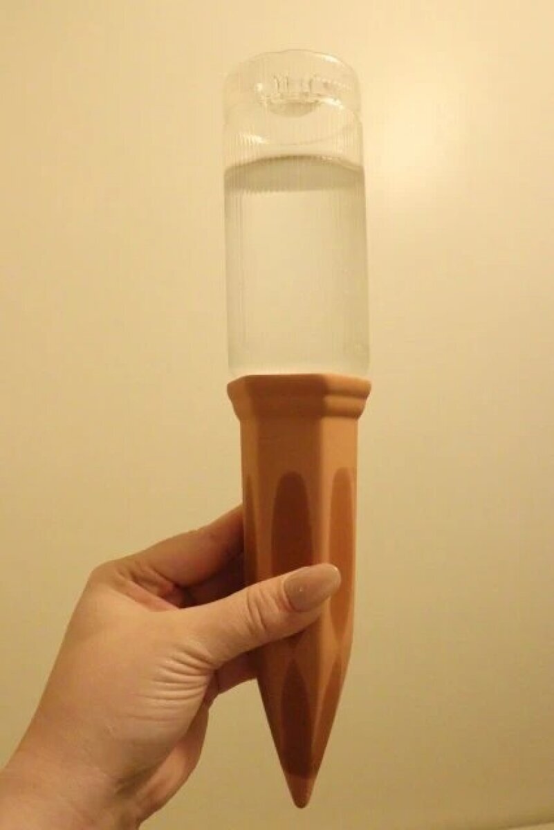 一個連接在裝滿水的塑膠瓶上的飲水器,拿在手上。 水を入れたペットボトルにウォーターディスペンサーを装着して手に持っている状態