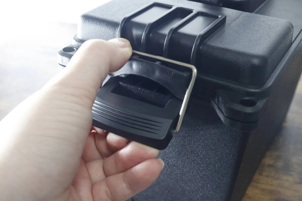 手で工具箱のロック部分を持ち上げて開けている様子