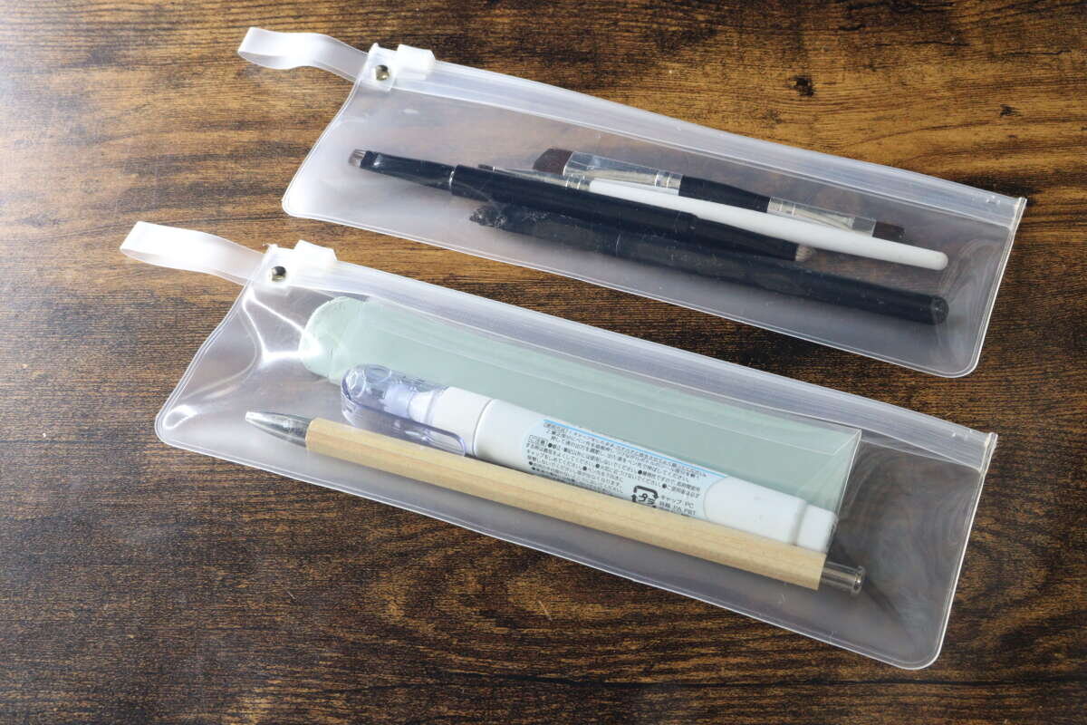 這兩個小袋子裡裝滿了細長的文具用品,例如鋼筆、化妝刷以及化妝品。 2つのポーチにそれぞれペンやメイクブラシなどの細長い文房具やコスメを入れた状態