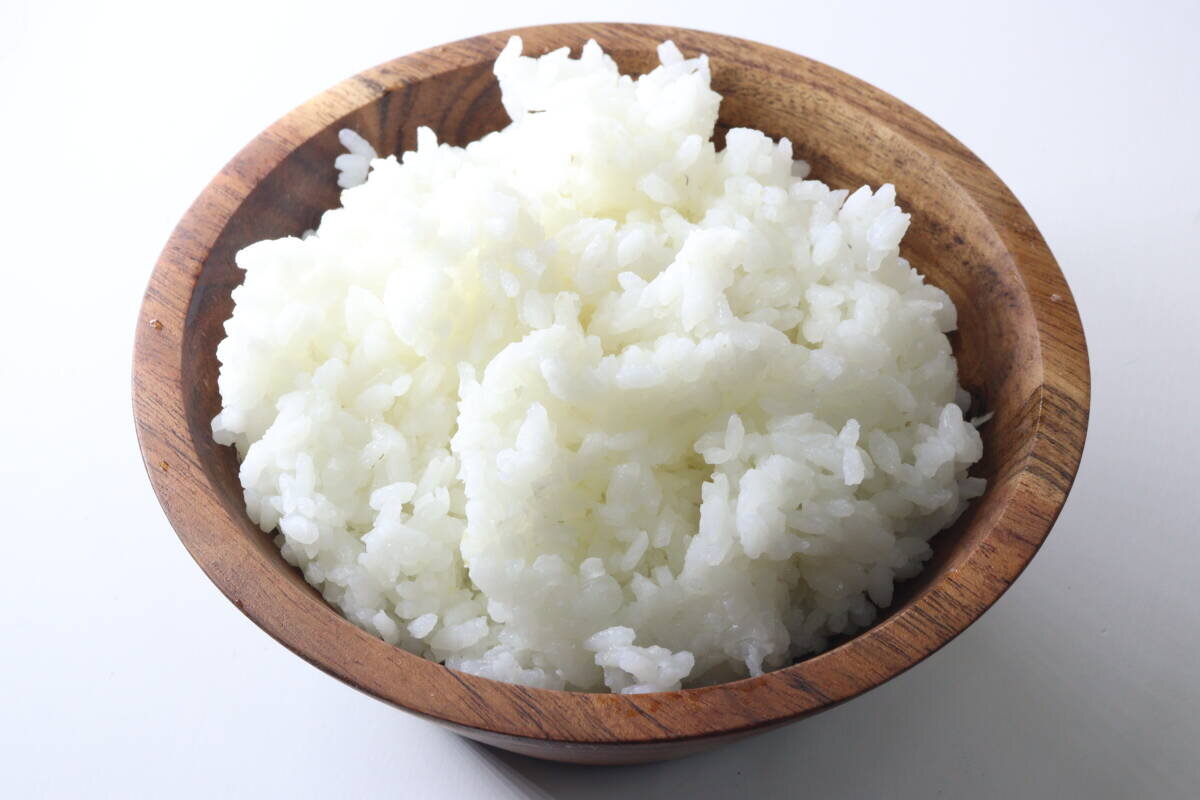 一個盛滿新鮮煮熟的白米飯的木碗。 木製のボウルに炊き上がった白いご飯がたっぷりと盛られている状態