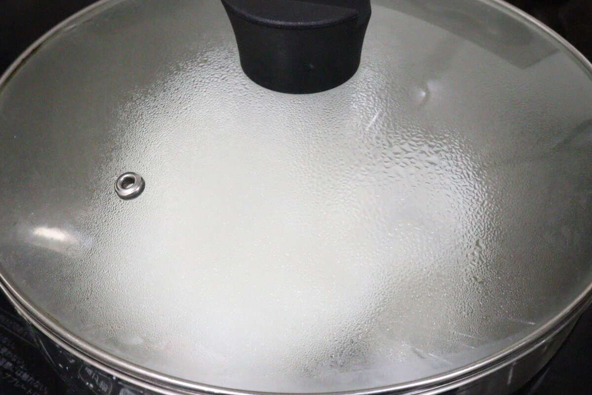 米飯在蓋著蓋子的鍋子裡蒸煮的場景。 フタをした鍋の中でご飯を蒸らしている調理中の様子