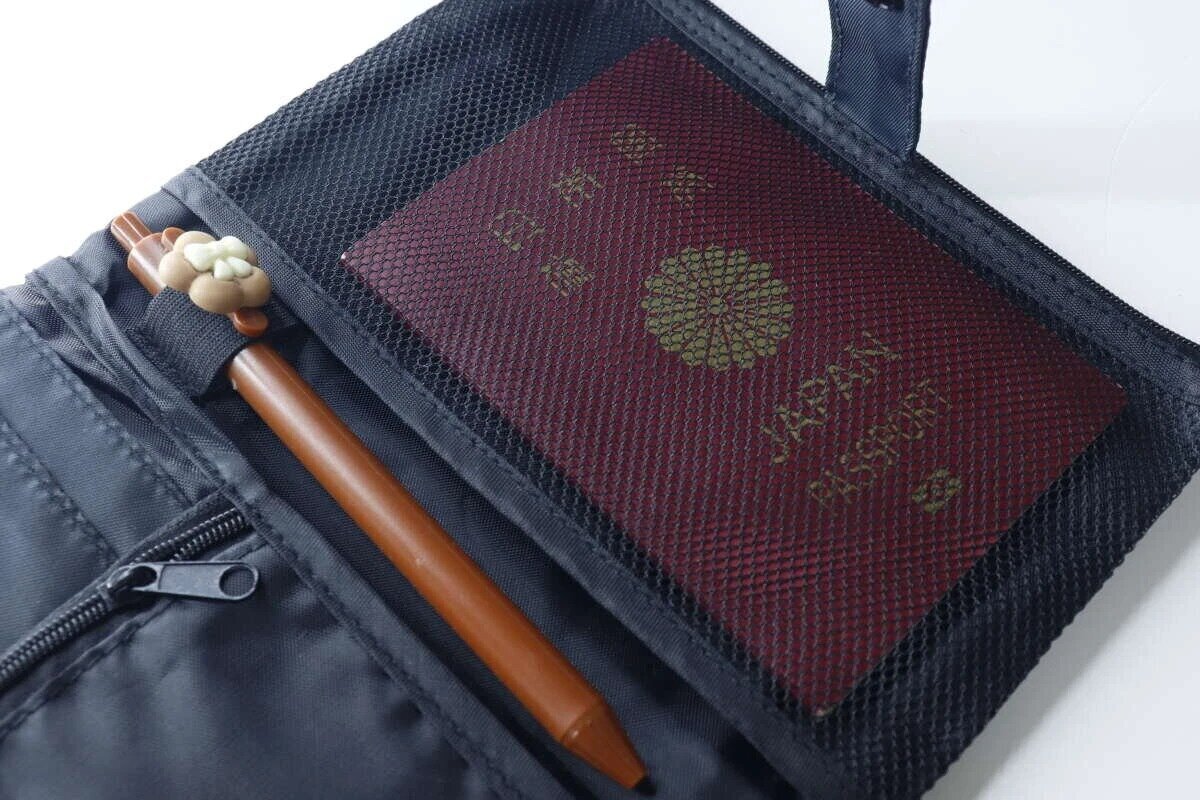 從上方俯視可以看到護照和鋼筆放在護照套的網狀口袋裡。 パスポートケースのメッシュポケットにパスポートとペンを入れた俯瞰