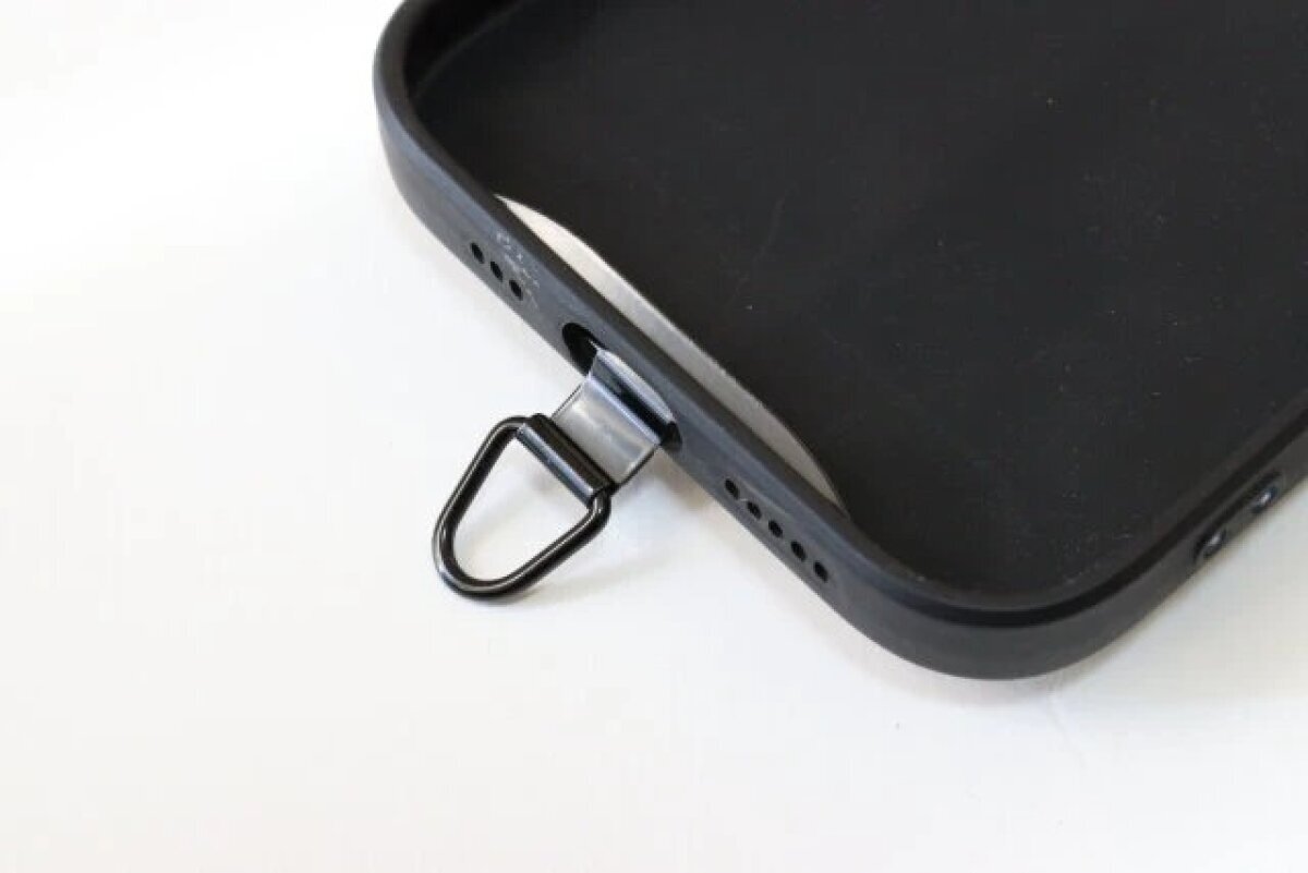 手機殼底部露出了掛鉤。 スマートフォンケースの下部からストラップホルダーのフックを出している様子