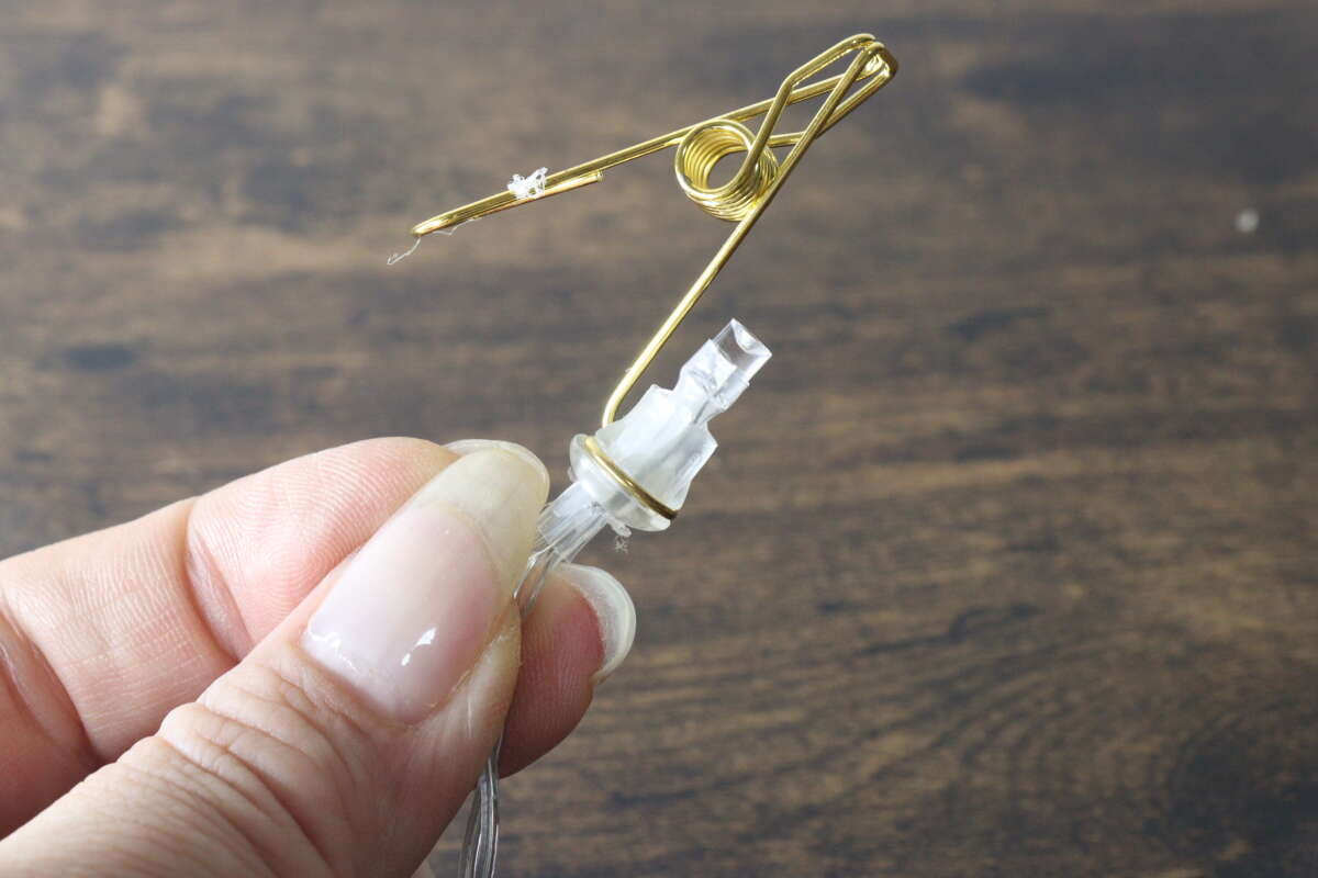 圖片顯示,金色夾子和 LED 燈連接器被握在手中。 ゴールドのクリップとLEDライトの接続部分を手に持って見せている様子