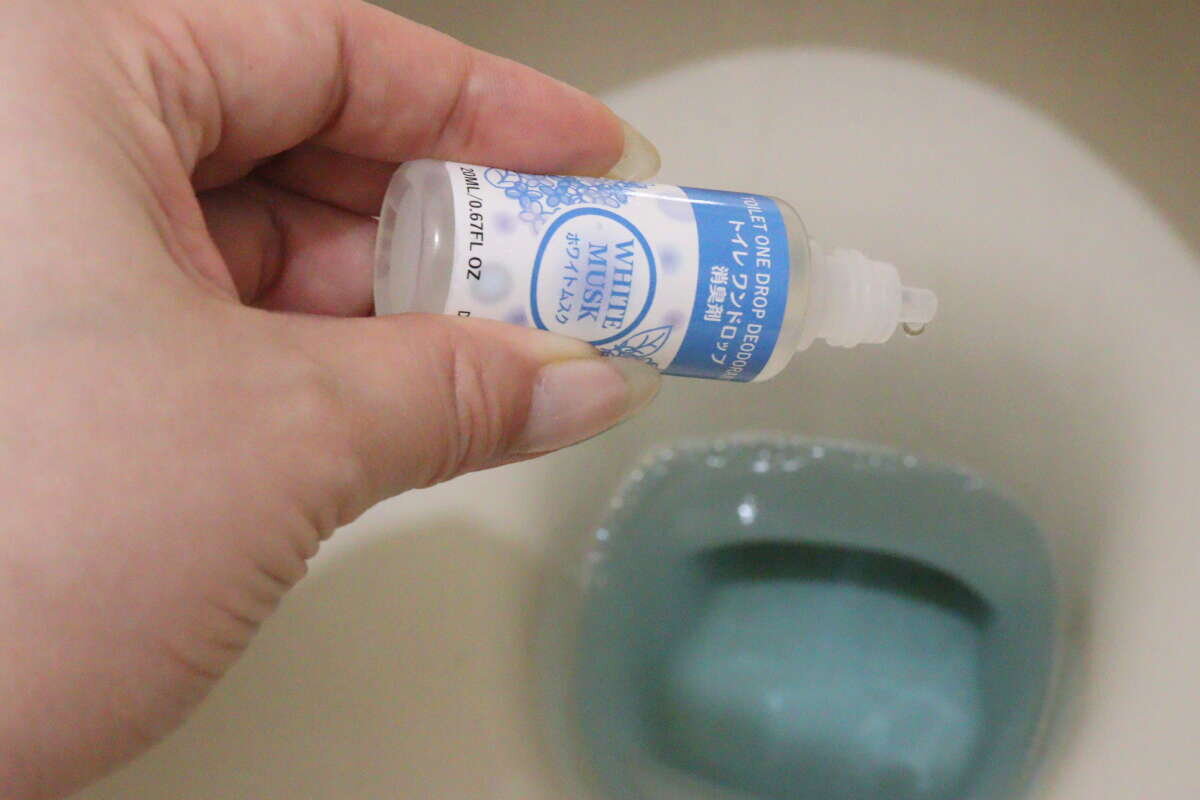 圖片顯示有人將除臭劑倒入馬桶水中。 便器の水たまり部分に消臭剤の液体を垂らしている様子