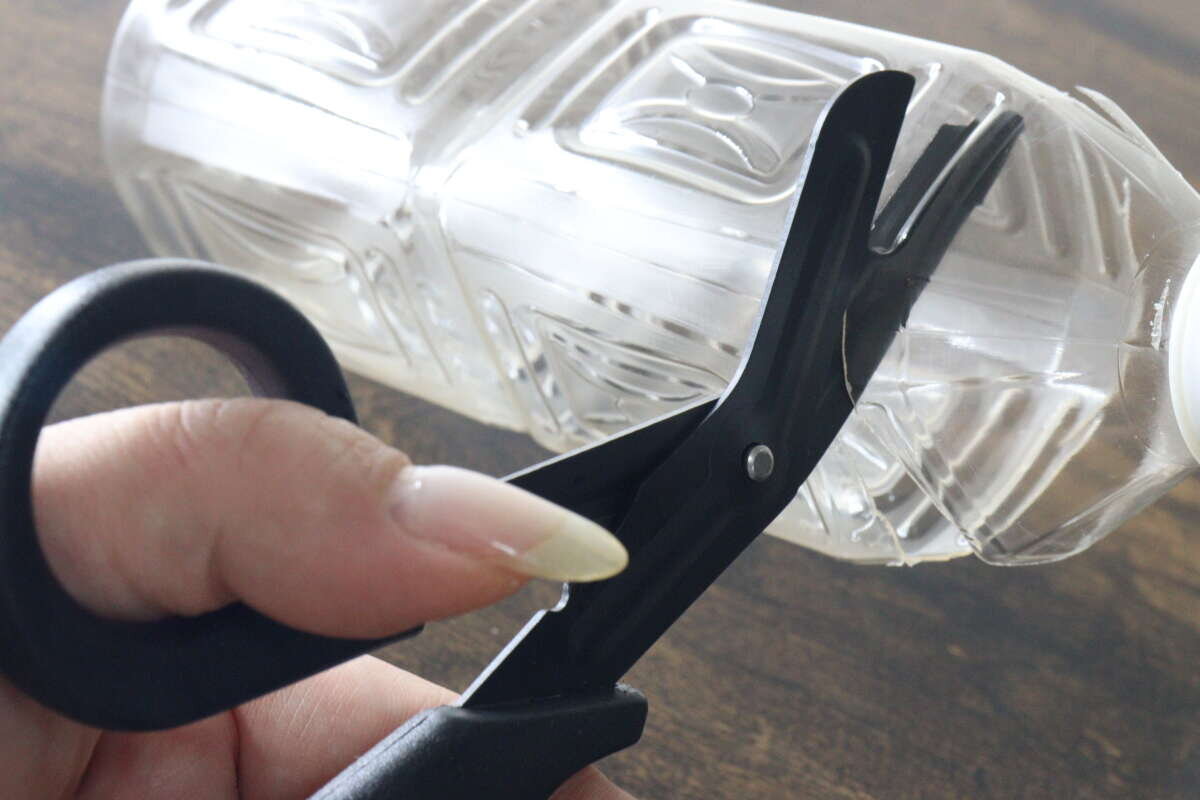 一個場景是,用黑色剪刀很容易就能剪開一個硬塑膠PET瓶。 固いプラスチック製のペットボトルを黒いハサミで難なくカットしている場面