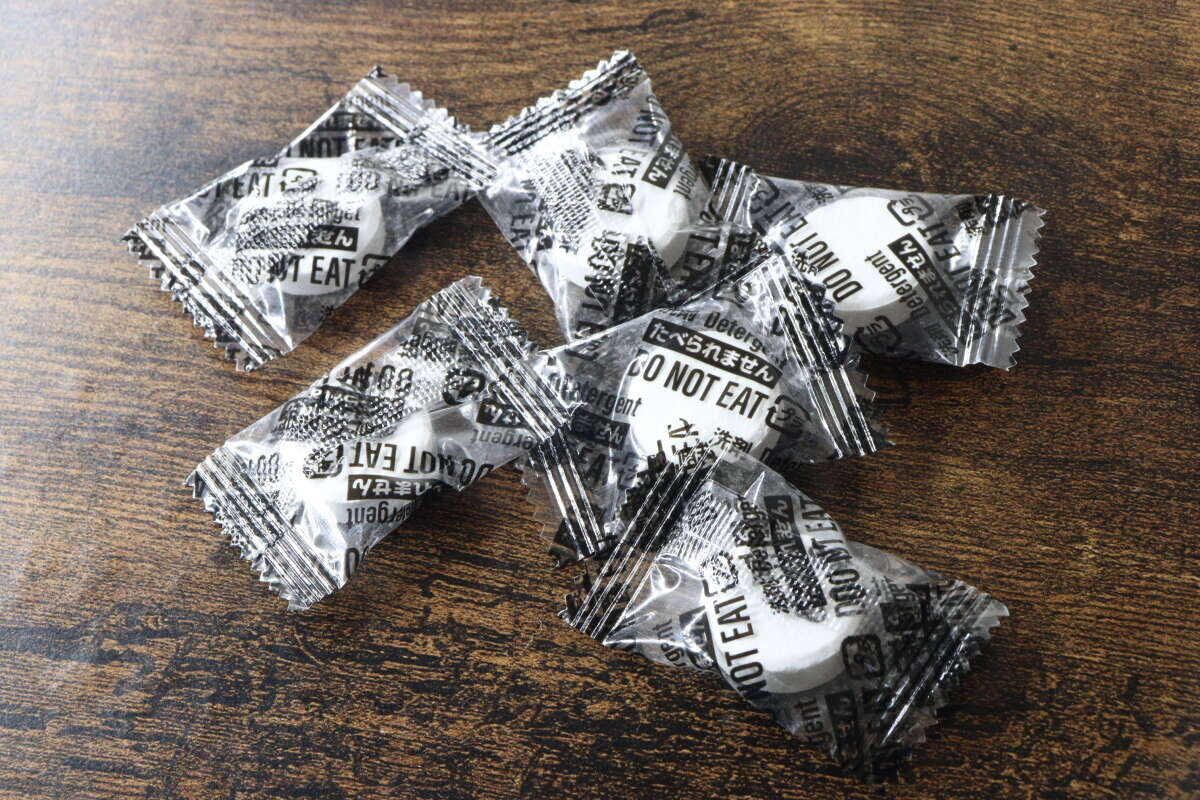 畫面中,幾片獨立包裝的白色片狀清潔劑整齊地排列著。 個包装された白い錠剤型クリーナーが複数並んでいる様子