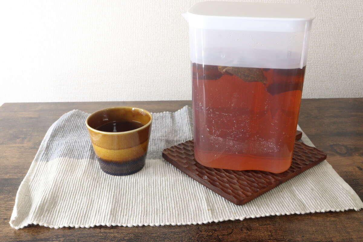 桌上放著裝滿茶水的茶壺和茶杯的整體視野。 お茶が入ったウォーターポットとマグカップがテーブルに置かれた全体像