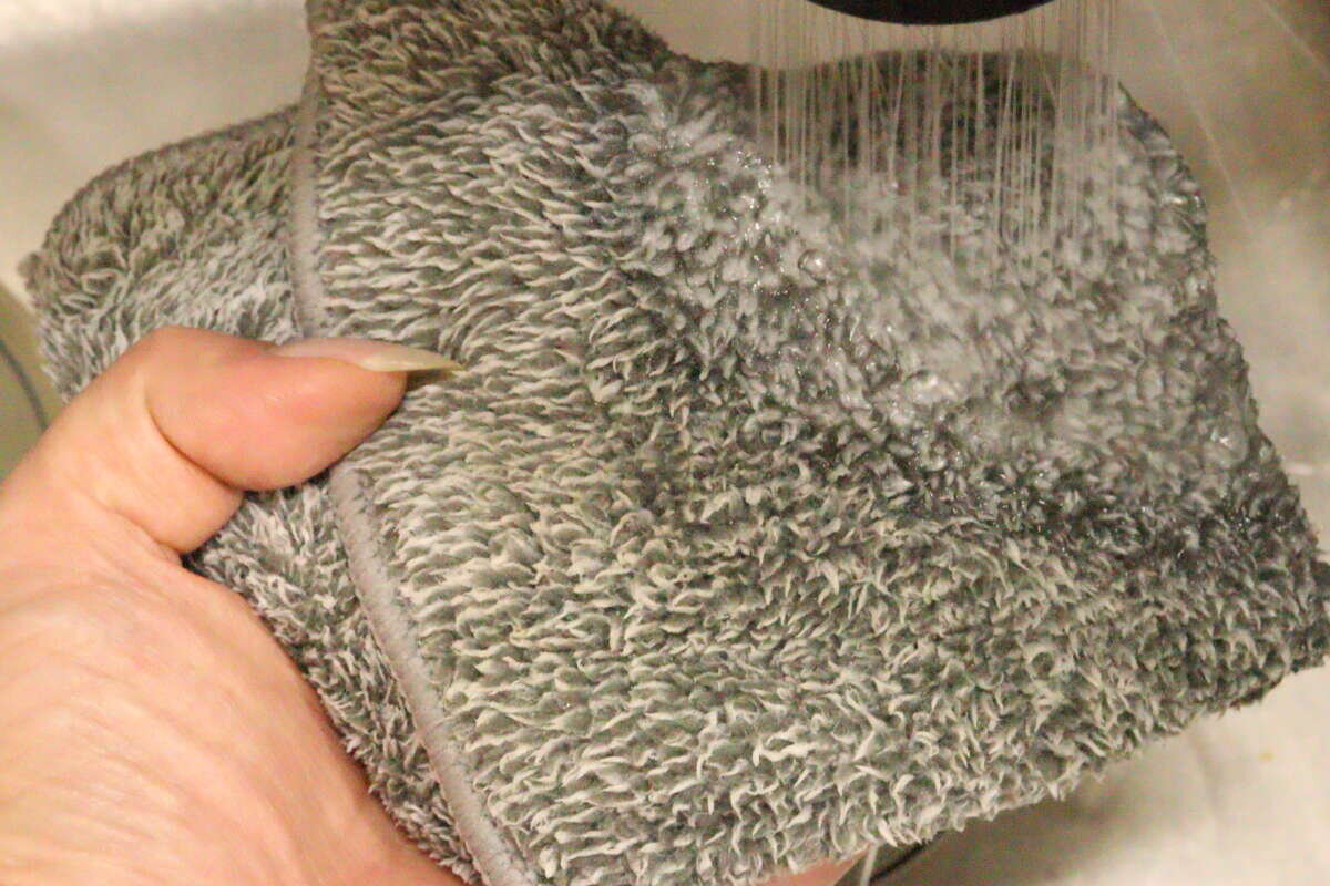 用過的髒抹布正在用自來水沖洗。 使用後の汚れたふきんを蛇口からの流水で洗い流している様子