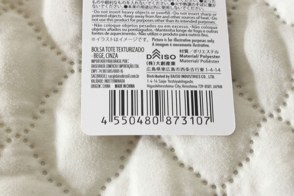 紙質標籤特寫,顯示產品材質和 JAN 代碼。 商品の材質やJANコードが記載された紙タグの接写