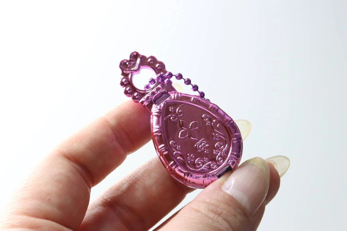 指で持ったジュエルキーホルダーの裏面にある、セボンスター風の花模様のレリーフ