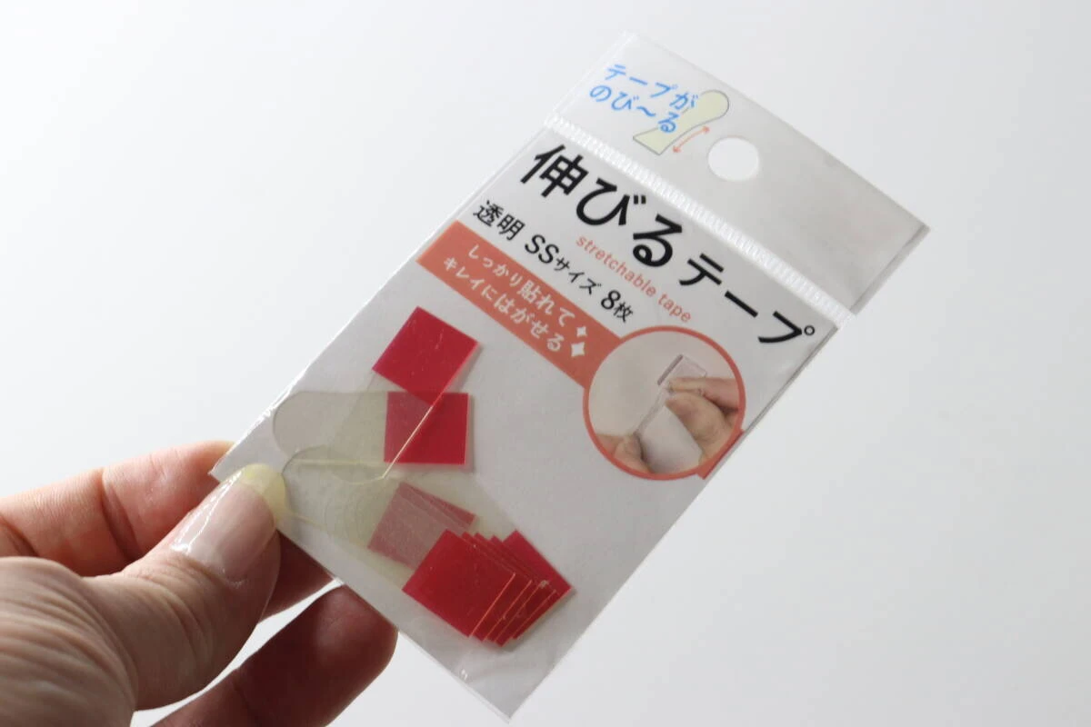 女性の手がダイソー「伸びるテープ」のパッケージを斜めに持っている様子 女性の手がダイソー「伸びるテープ」のパッケージを斜めに持っている様子