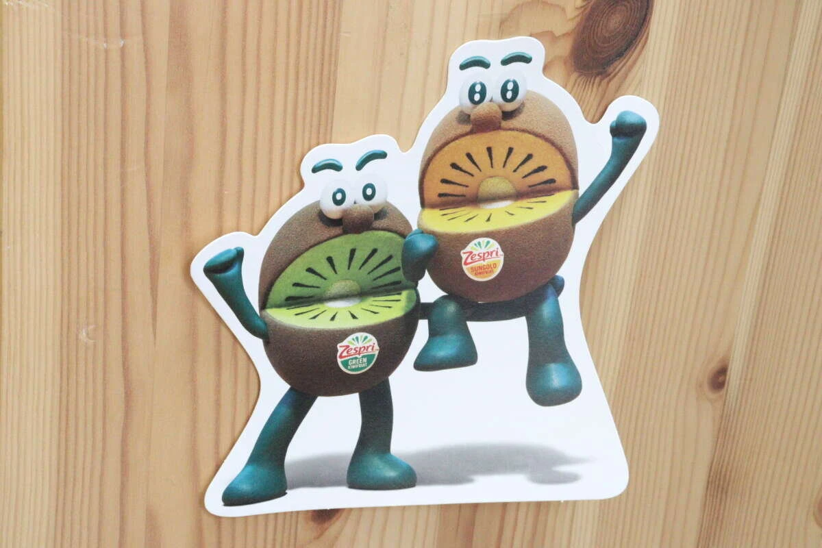 木目調の壁に、キウイのキャラクターが描かれたカードが透明なテープで貼り付けられている 木目調の壁に、キウイのキャラクターが描かれたカードが透明なテープで貼り付けられている