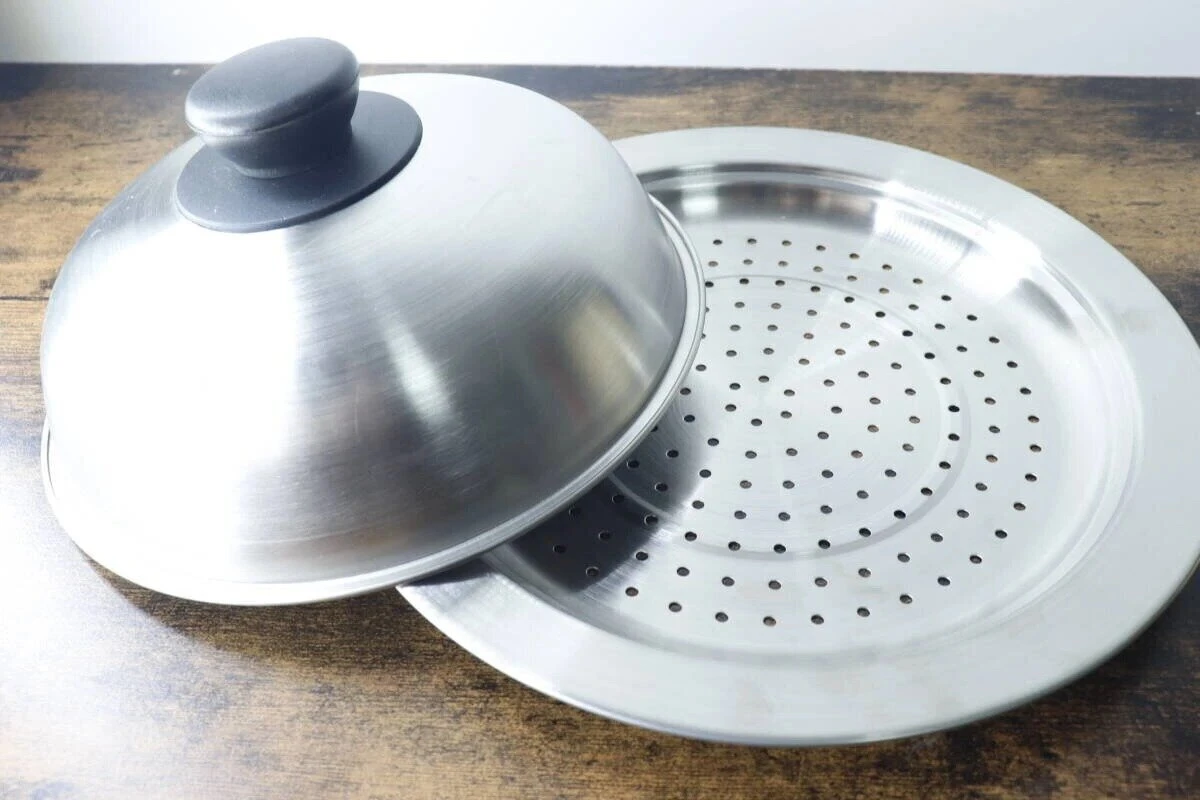 ステンレス製の蒸しプレートとドーム型の蓋が木目調のテーブルに置かれている ステンレス製の蒸しプレートとドーム型の蓋が木目調のテーブルに置かれている