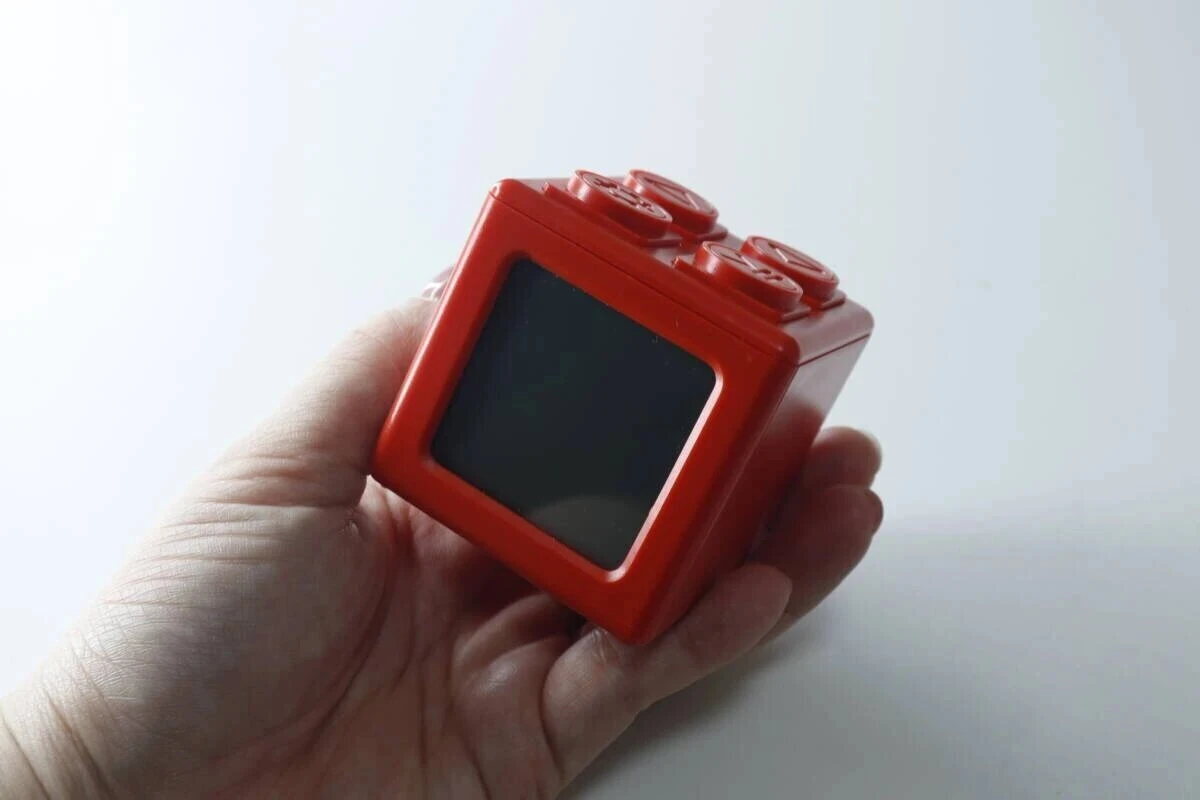 赤いブロック型デジタルタイマー時計を手のひらに乗せて持っている 赤いブロック型デジタルタイマー時計を手のひらに乗せて持っている