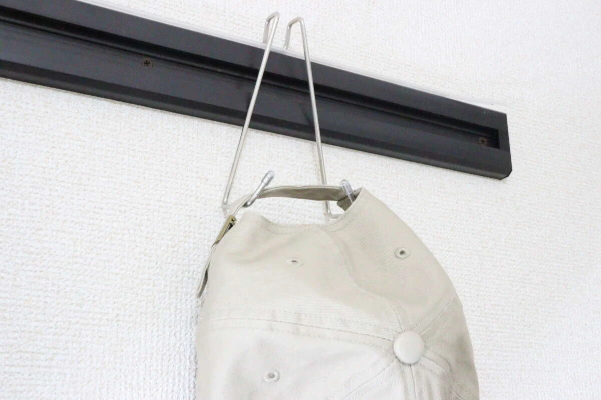 鴨居用便利フックにベージュのキャップを掛けている様子。