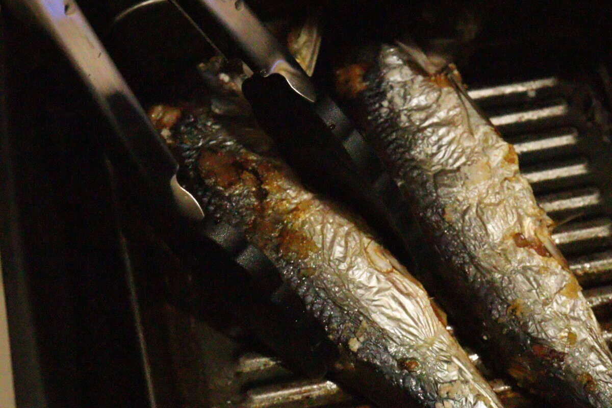 魚焼きグリルで焼かれた魚をダイソーのシリコーントングで優しく掴んでいる様子 魚焼きグリルで焼かれた魚をダイソーのシリコーントングで優しく掴んでいる様子