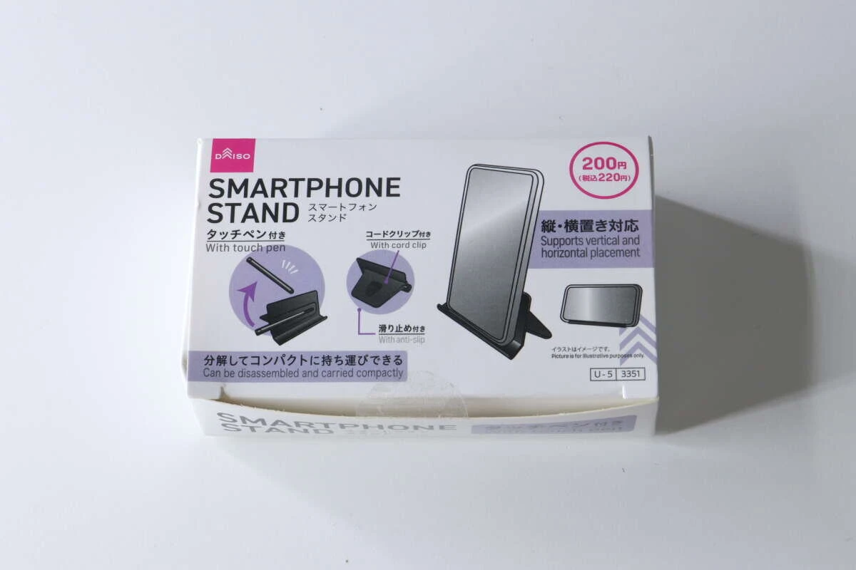 白い背景に置かれた、ダイソーのスマホスタンド(タッチペン付)のパッケージ。 白い背景に置かれた、ダイソーのスマホスタンド(タッチペン付)のパッケージ。