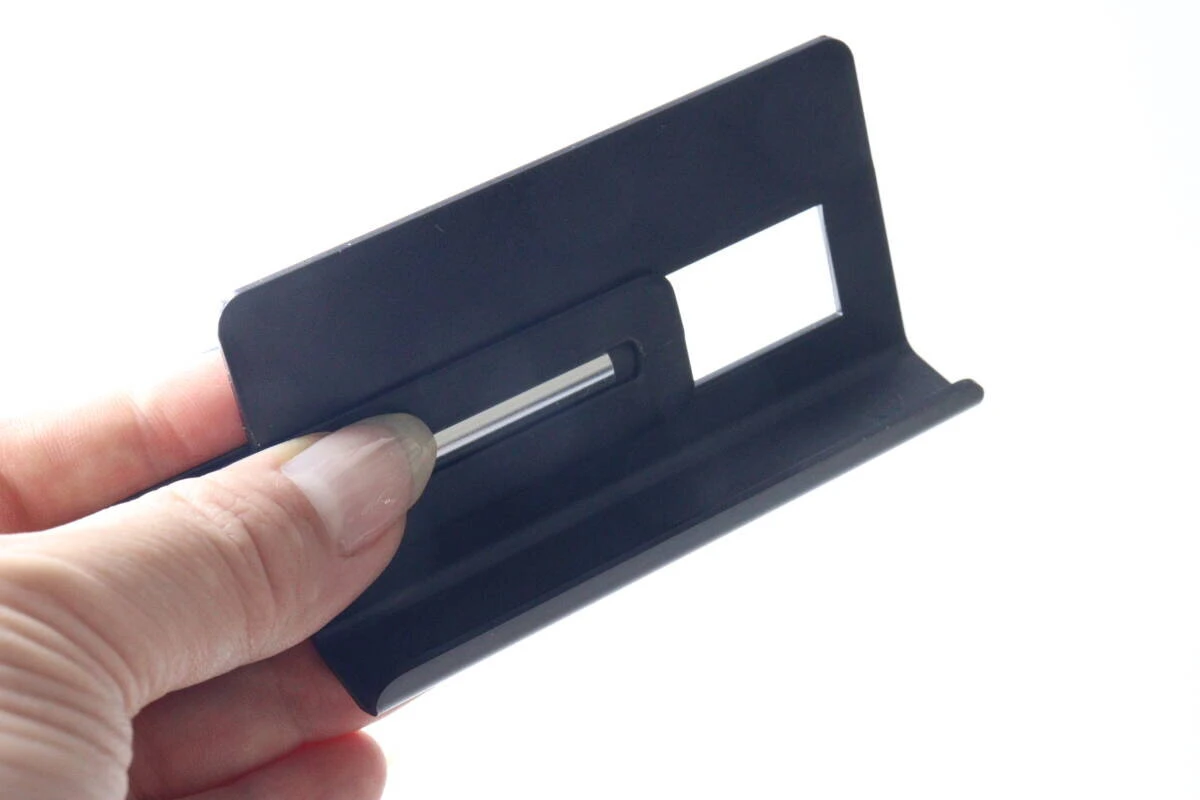 指で黒いスマホスタンドのパーツを組み立てている様子。 指で黒いスマホスタンドのパーツを組み立てている様子。