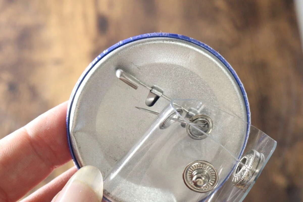 缶バッジのピンをクリアホルダーのハトメに通して装着する手元 缶バッジのピンをクリアホルダーのハトメに通して装着する手元