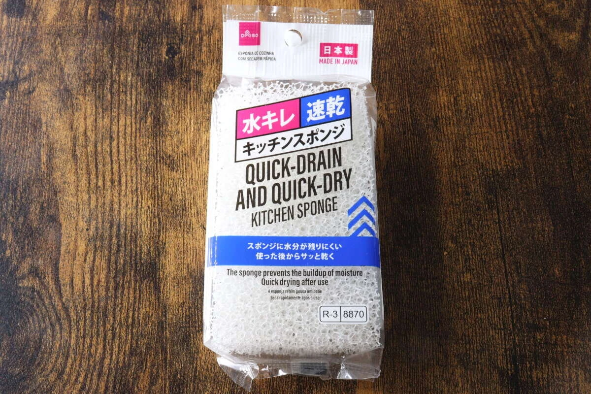 木目調のテーブルに置かれた、ダイソー「水キレ速乾キッチンスポンジ」のパッケージ