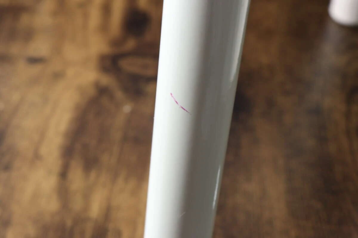 白い椅子の脚に付着した、ピンク色の油性ペンらしき汚れのアップ 白い椅子の脚に付着した、ピンク色の油性ペンらしき汚れのアップ
