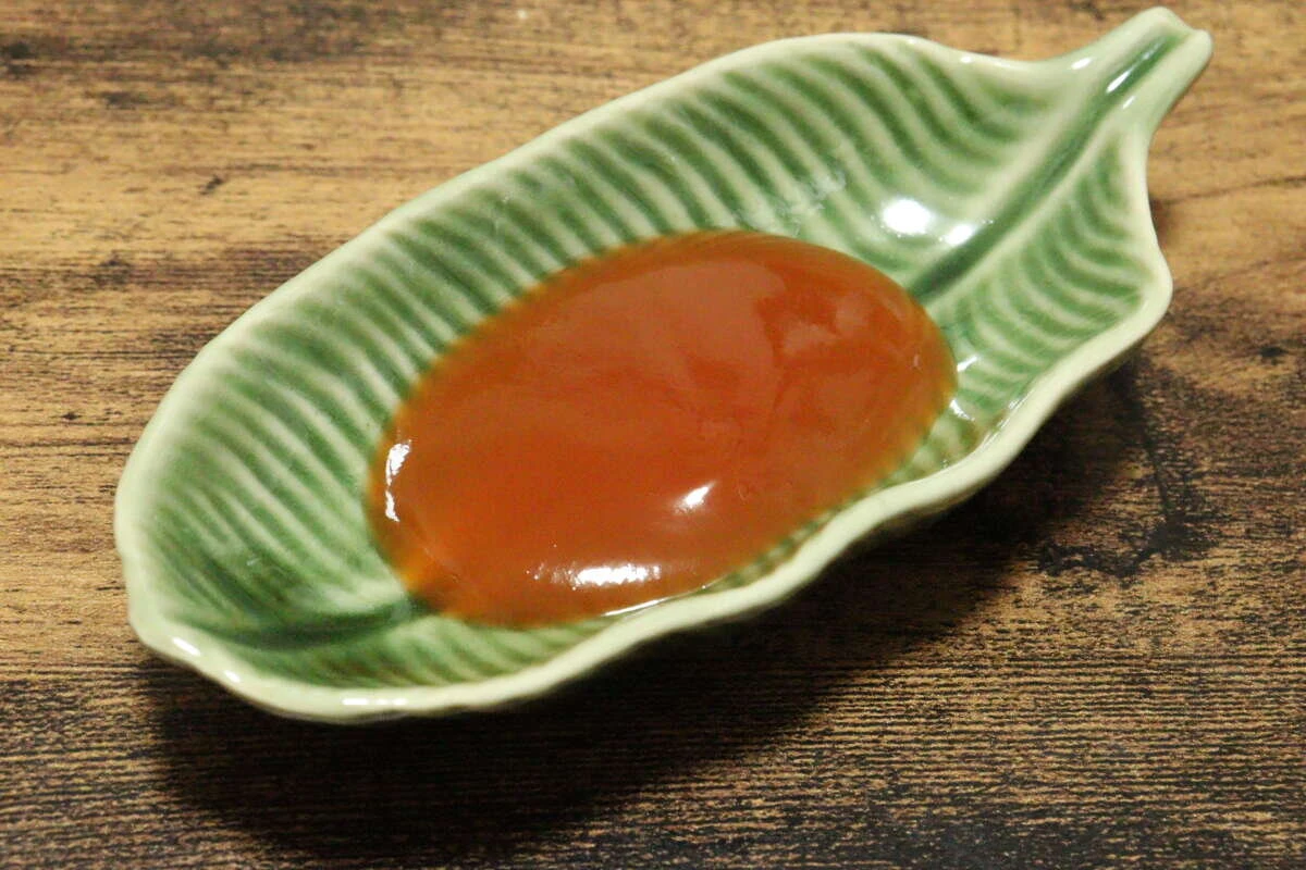葉っぱ型の緑色の小皿に盛られたオレンジ色のチリソース
